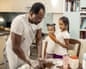 Father cooking in a kitchen with his two daughters.
