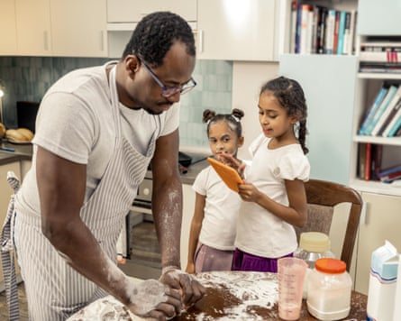 A father cooks with his two cute daughters