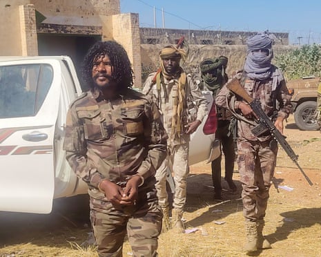 Group of paramilitaries with assault rifles arresting another paramilitary wearing the same combat fatigues