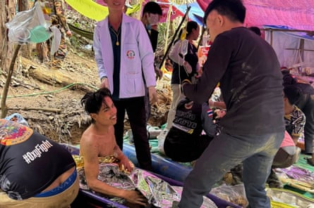 A man smiles while seated on the ground.