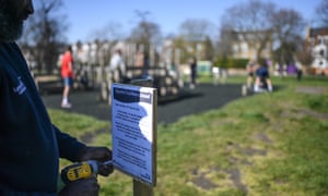 A council worker puts up a sign notifying the closure of an outdoor gym on Clapham Common in London.