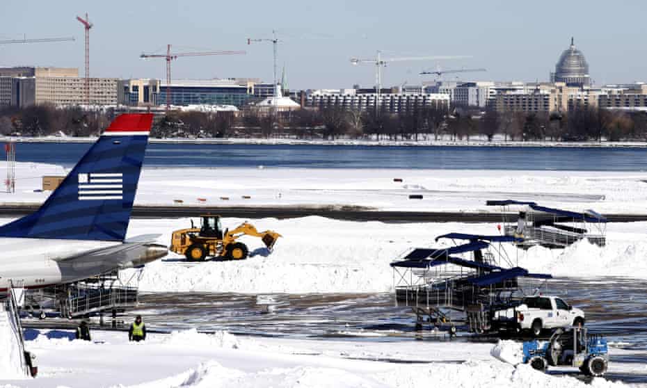 Workers clear snow on the tarmac at Ronald Reagan national airport, Washington DC, following the blizzard.