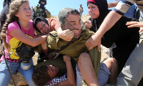 Tamimi family members try to pull the Israeli soldier off Mohammed, 11, during protests against Palestinian land confiscation in Nabi Saleh, West Bank.