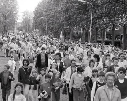Black and white image of a crowd of people walking along a road
