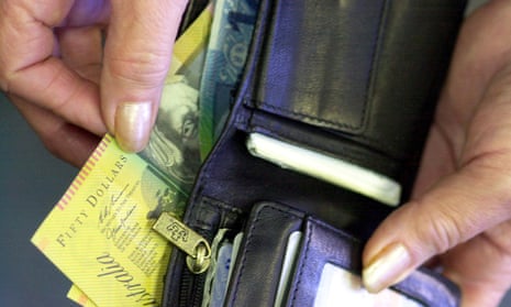 A hand placing Australian notes into a wallet
