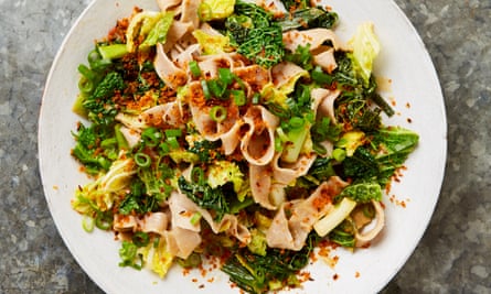 Closeup of a wide ribbons of buckwheat pasta with chopped green cabbage and breadcrumbs, on a white plate.