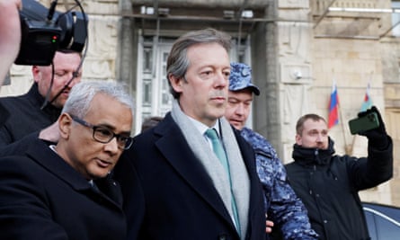 Nigel Casey being escorted past people taking photographs and video footage