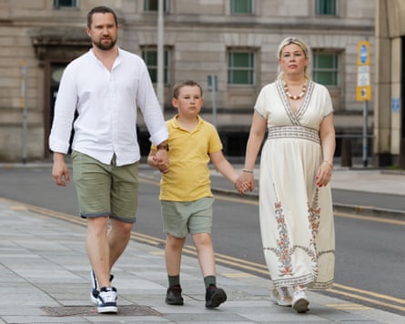 Oleksandr, Viktoriia and Vladimir walk along a pavement holding hands