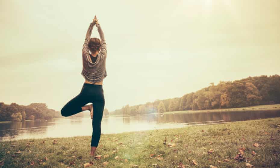 A woman holds a yoga pose as she practises outdoors