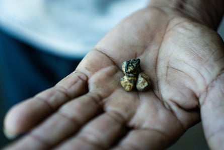 A man’s hand holding small stones coloured black and gold