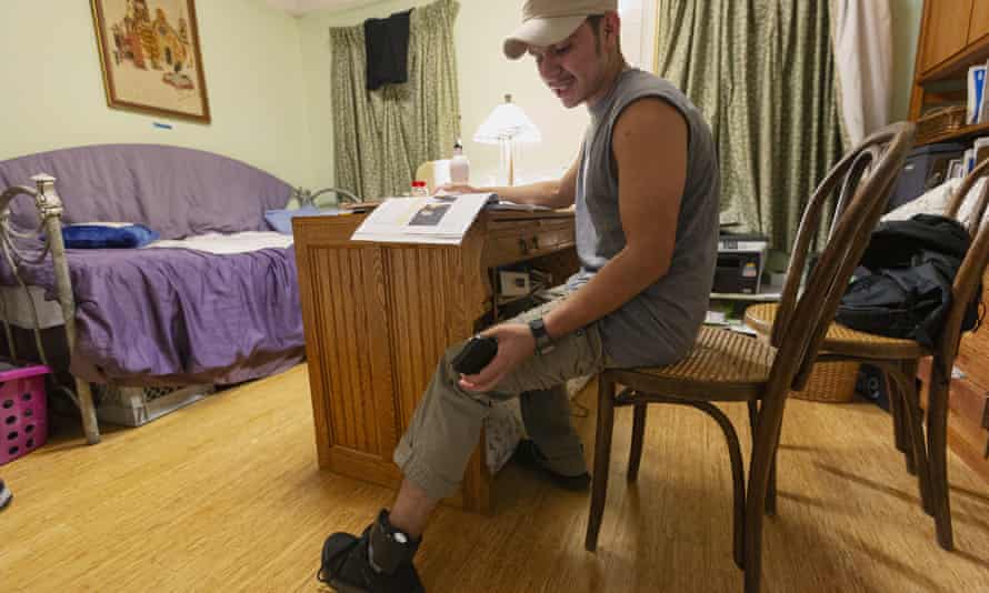 An asylum seeker checks the battery level on his ankle monitor as he works on English language lessons.