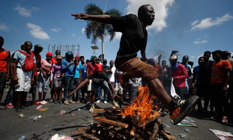 A man jumps over a fire during a voudou ceremony to grant protection to the people, as protesters called for the resignation of President Jovenel Moïse.