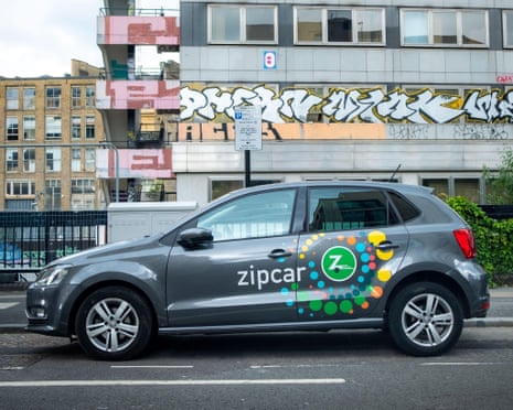A Zipcar parked in front of a graffiti covered building in London.