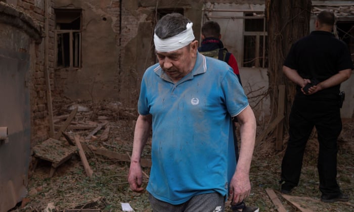 A man injured during a Russian military strike walks next to his residential building in Kharkiv