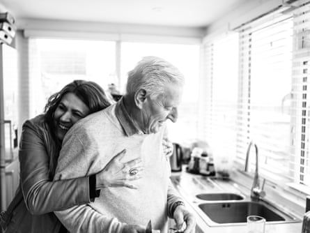 Ieda hugs her husband, John, in the kitchen