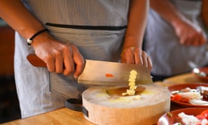 Someone chopping baby corn with a wooden handled blade