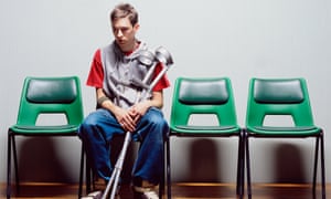 Young man with crutches sitting on hospital chairs
