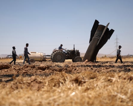 Farmers near the town of Najha in Syria douse a burned agricultural field next to a projectile from Iranian missile launches.