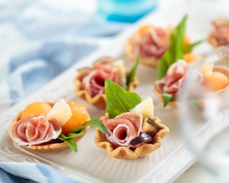 Appetisers with prosciutto crudo, melon balls, figs, parmesan cheese and basil