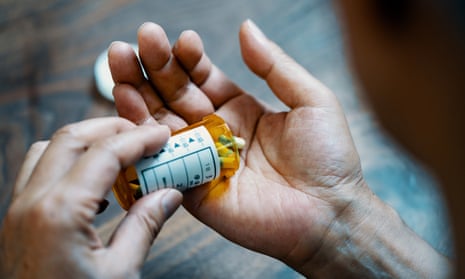 A male  holding a pill bottle pouring medication into his hand