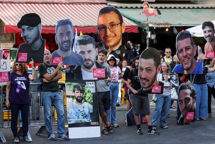 People hold up cutout pictures of young smiling people