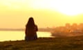Back view backlight portrait of a single woman watching a sunset on the city with a warm light in the background<br>M1913C Back view backlight portrait of a woman watching a sunset on the city with a warm light in the background with view of water and buildings