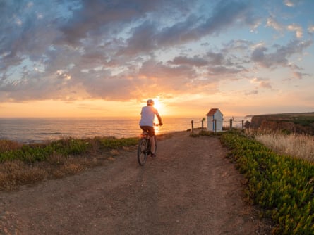 A cyclist at sunset on the coastal bike path in the Alentejo, Portugal.