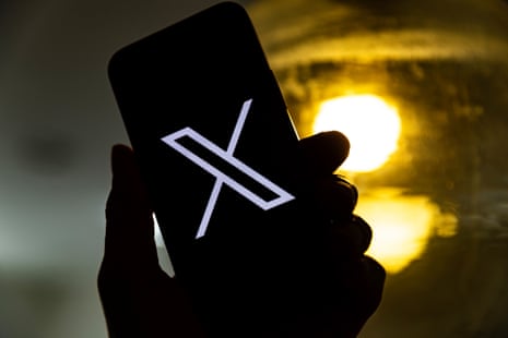 A user holding a mobile phone displaying the 'X' logo.