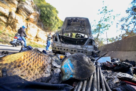Singed protective helmet on the floor beside the destroyed car