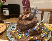 A large chocolate cake with eyes, covered in coloured sugary pieces and topped with a large "9" candle