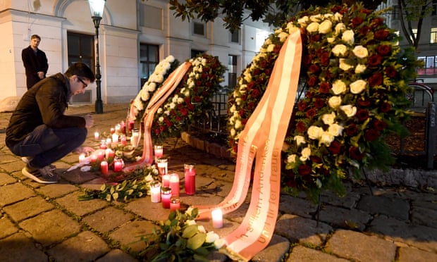 A man lights a candle next to floral tributes at the scene of the attacks in Vienna.