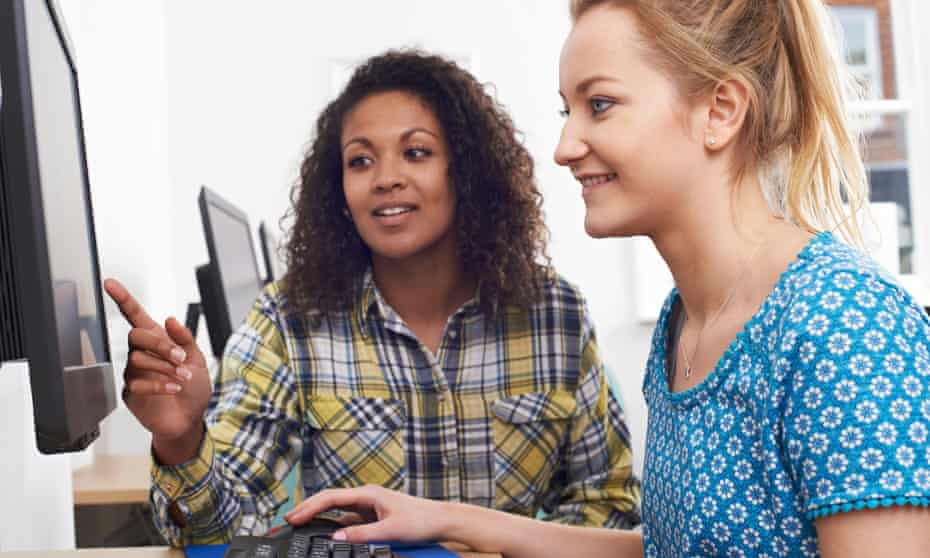 Businesswoman Giving Computer Training to younger woman In Office