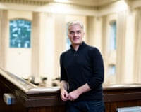 Conductor Ed Gardner smiles near a wooden railing in an ornate hallLondon; Philharmonic; Orchestra; behind; the; scenes; BTS; LPO; Music; Woodwind; Strings; Brass; Timpany; Percussion; String; Harp; Violin; Cymbals; Drums; Trumpet