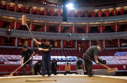 Yobidashi performing tataki (pounding) with wooden mallets to compact the soil, clay and cement mixture as they help prepare the dohyo
