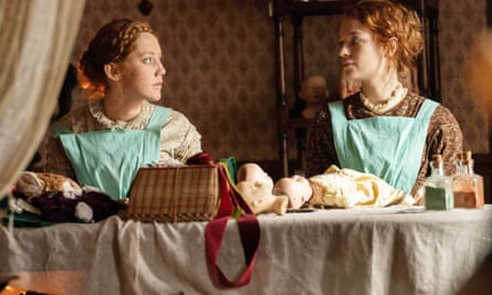 Mirren Mack and Esmé Creed-Miles in period costumes at a table with dolls on.