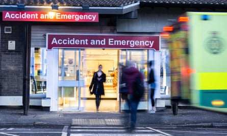 Ambulance and people outside an accident and emergency unit; the image is blurred and anonymous but figures are seen going in and out of an illuminated doorway