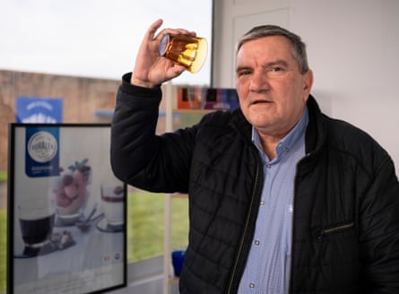 Man holds orange glass tumbler.