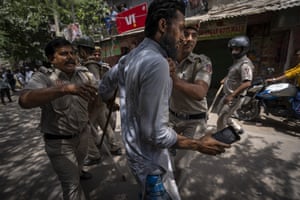 Police detain a Muslim resident who used his mobile phone to record the demolition of Muslim-owned shops at the site of Saturday’s violence in New Delhi’s north-west Jahangirpuri neighbourhood