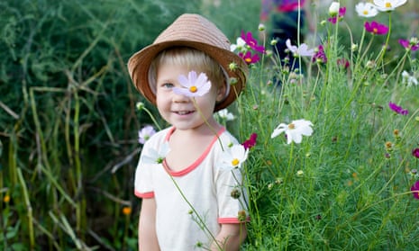 4 years old blondy boy over beautiful garden with summer flowers