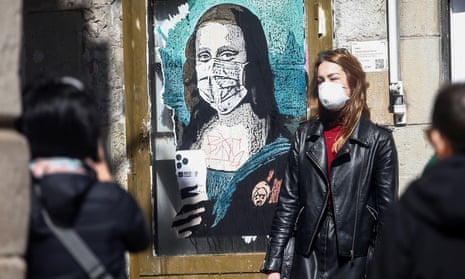 A woman poses next to a work by urban artist Tvboy in Barcelona, Spain on Monday