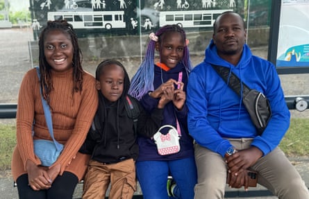 A family of four sit smiling at a bus stop