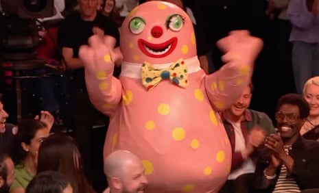 An inflatable pink creature with yellow spots in the middle of an audience