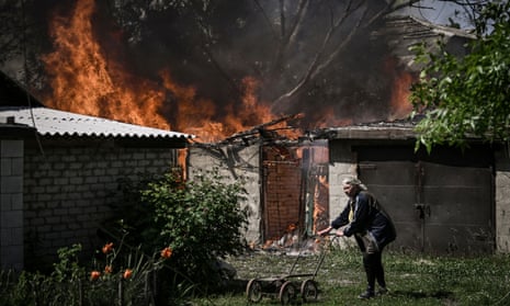 An elderly woman walks away from a burning house garage after shelling in the city of Lysychansk.