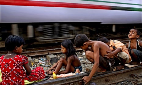 Bangladeshi children play on a railway line while a train passes by at Tejgaon, Dhaka