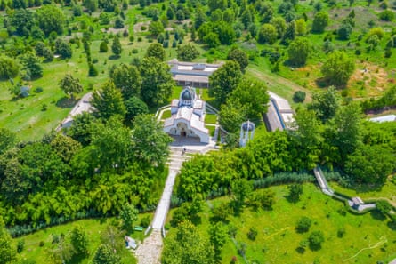 A shot of a white church surrounded by green trees