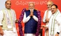 Three men place a purple garland over Narendra Modi as he holds up his hands in prayer
