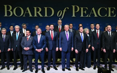 A group of men in suits smile in front of a backdrop that reads 'Board of Peace'