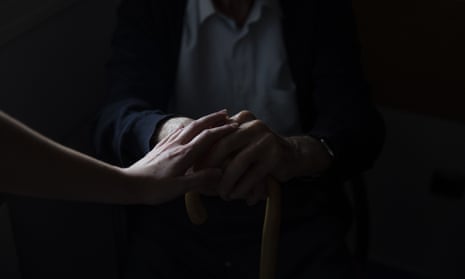 Stovk shot of a younger person's hands clasped over an older person's hands, artistically lit