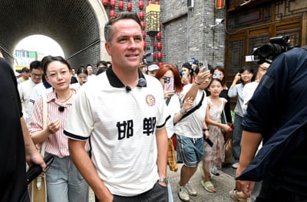 Man walks in a crowded street as people race to photograph him