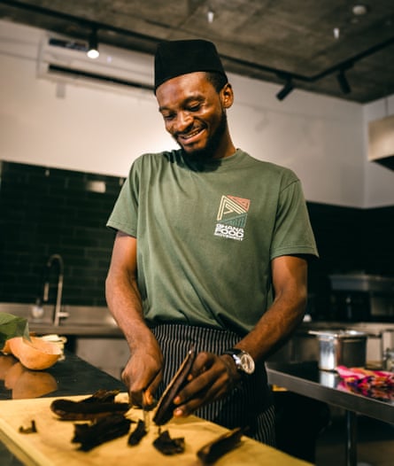 Abiro Wisdom smiling while slicing food wearing GFM T-shirt